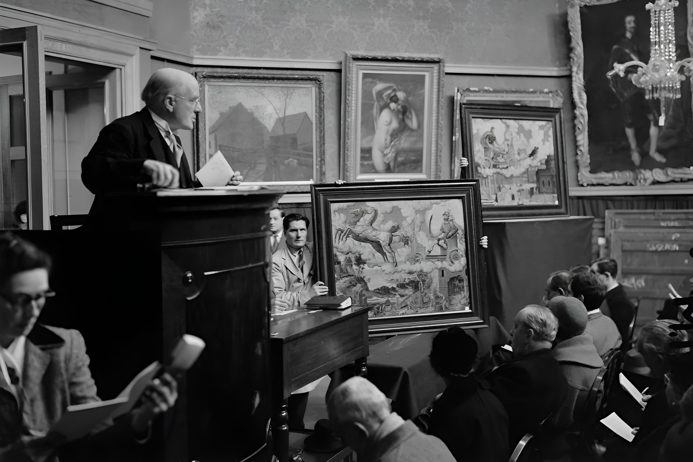 Administrerende direktør for auksjonshuset Christie’s, Sir Alec Martin (1884-1971), ved en talerstol under en kunstauksjon, London, 9. desember 1955.